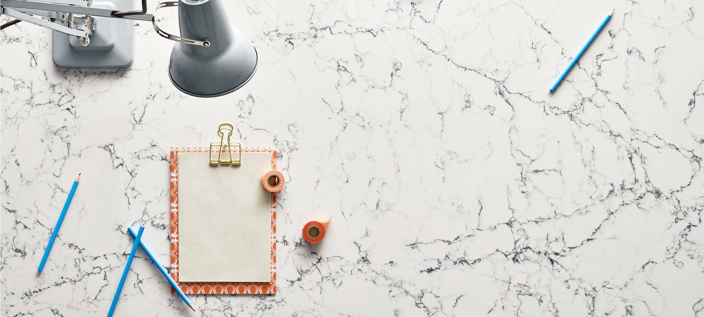 notepad on white attica counter with blue pencils
