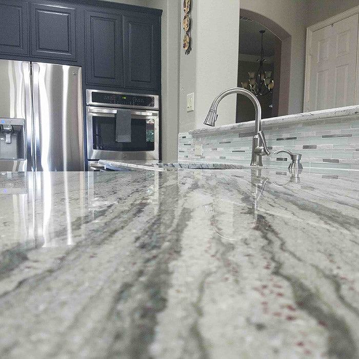dark grey cabinets with light green grey river white granite countertops and stainless steel sink