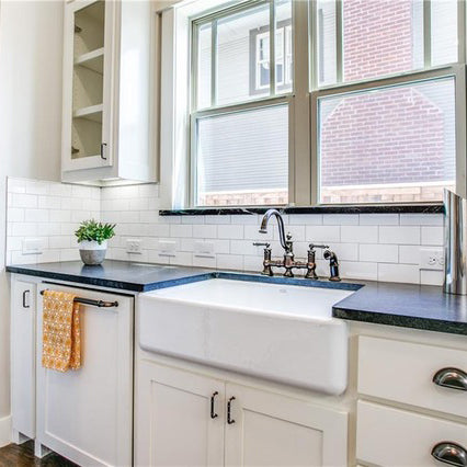 Dark soap stone with white kitchen cabinets, white large cast iron farm sink