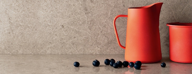 red cup with blueberries on the symphony grey countertops with full backsplash