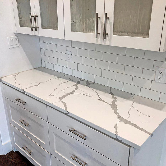 calacatta sponda quartz waterfall kitchen countertops with white cabinets