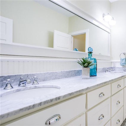 carrara marble bathroom countertops with white oval sinks and white cabinets